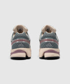 Rear view of gray and beige adidas sneakers with mauve accents on a plain background