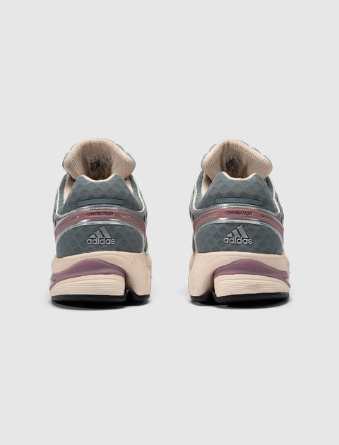 Rear view of gray and beige adidas sneakers with mauve accents on a plain background