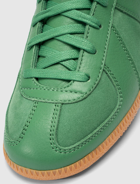 Close-up of green leather sneaker with matching laces and gum rubber sole