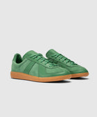 Green leather low-top sneakers with gum soles on a neutral background