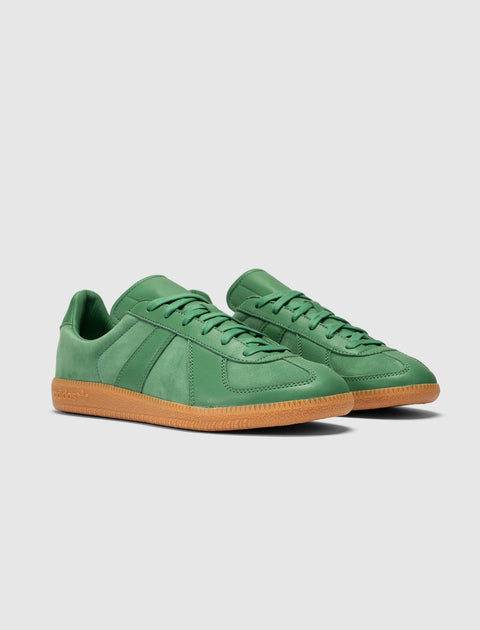 Green leather low-top sneakers with gum soles on a neutral background