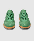 Pair of green leather sneakers with gum soles on a plain background