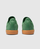Back view of green suede sneakers with gum rubber soles on a light background