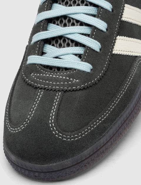 Close-up of grey suede sneaker with cream stripes, blue laces, and textured sole