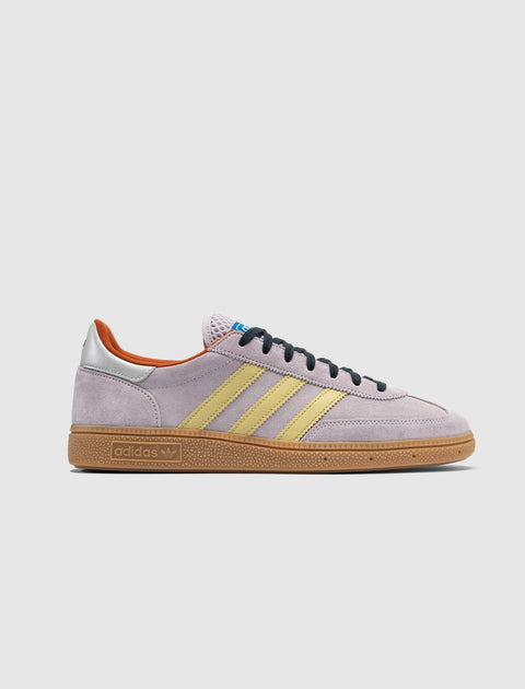 Lilac suede sneaker with yellow stripes, gum sole, silver heel tab, and black laces
