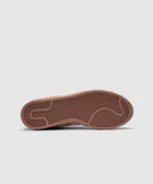 Close-up of brown sneaker outsole with zigzag tread pattern on grey background