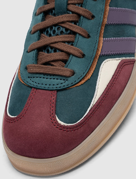 Close-up of a multicolor suede sneaker with navy, burgundy, and purple stripes detail