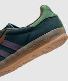Close-up of adidas sneaker in navy, green, purple, and gum sole, side profile