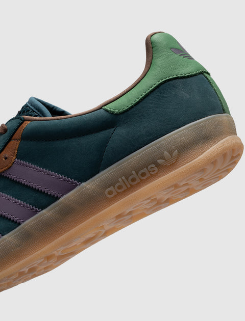 Close-up of adidas sneaker in navy, green, purple, and gum sole, side profile