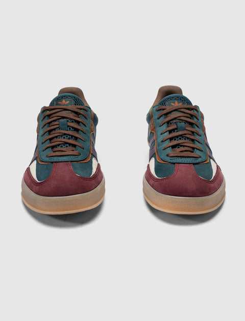 Pair of suede low-top sneakers in teal, navy, and burgundy with gum soles on white background