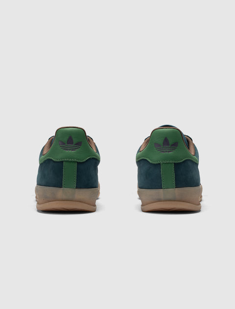 Rear view of green and navy suede sneakers with gum sole on white background