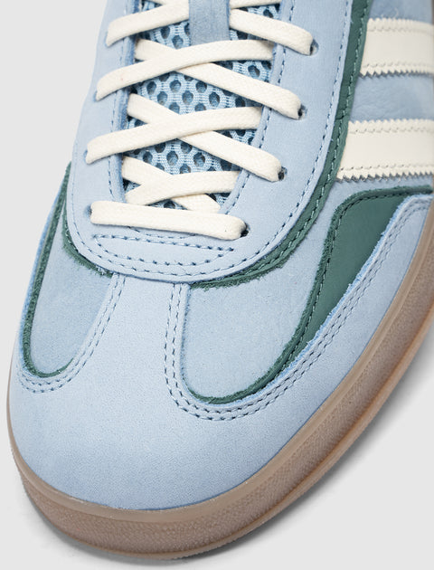 Close-up of blue suede sneaker with white laces, mesh tongue, and gum outsole