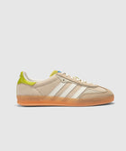 Cream and green suede low-top sneaker with white stripes and gum sole on light background