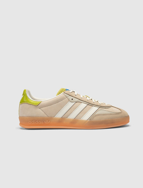 Cream and green suede low-top sneaker with white stripes and gum sole on light background