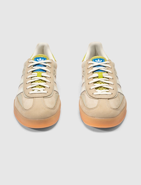 Cream and green low-top sneakers with gum soles, white stripes, and blue tongue branding