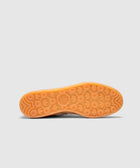 Bottom view of sneaker with translucent gum sole and circular tread pattern against grey background