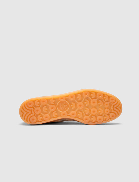 Bottom view of sneaker with translucent gum sole and circular tread pattern against grey background