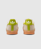 Beige and green sneakers with gum soles, viewed from the back on a white background.