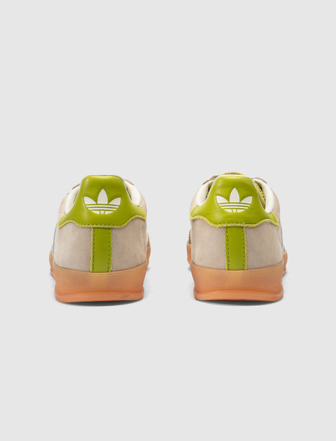 Beige and green sneakers with gum soles, viewed from the back on a white background.