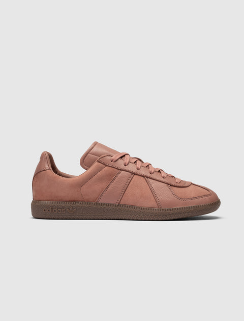 Salmon pink low-top leather sneaker with textured brown sole on white background