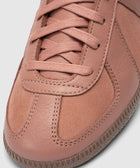 Close-up of salmon pink sneaker with suede and leather panels, laces, and textured sole