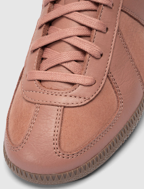 Close-up of salmon pink sneaker with suede and leather panels, laces, and textured sole