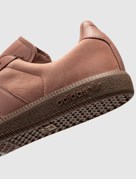 Close-up of salmon pink Adidas sneaker with textured sole and logo, streetwear footwear