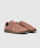 Salmon pink low-top sneakers with suede panels and textured rubber sole on white background