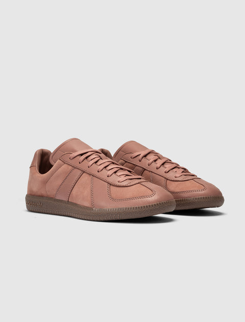Salmon pink low-top sneakers with suede panels and textured rubber sole on white background
