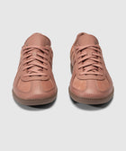 Pair of salmon pink low-top leather sneakers with gum soles on white background