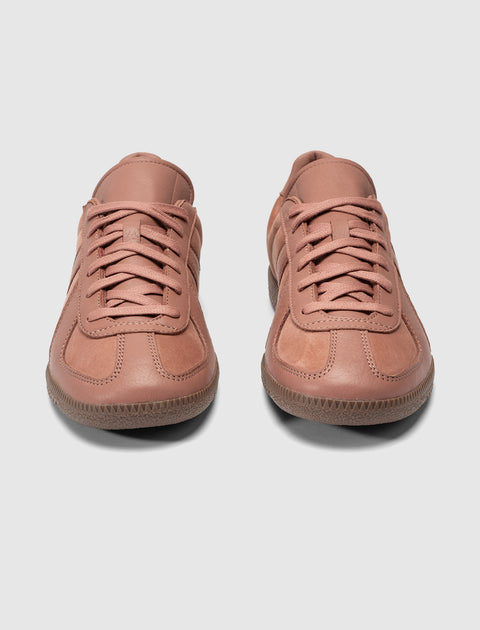 Pair of salmon pink low-top leather sneakers with gum soles on white background