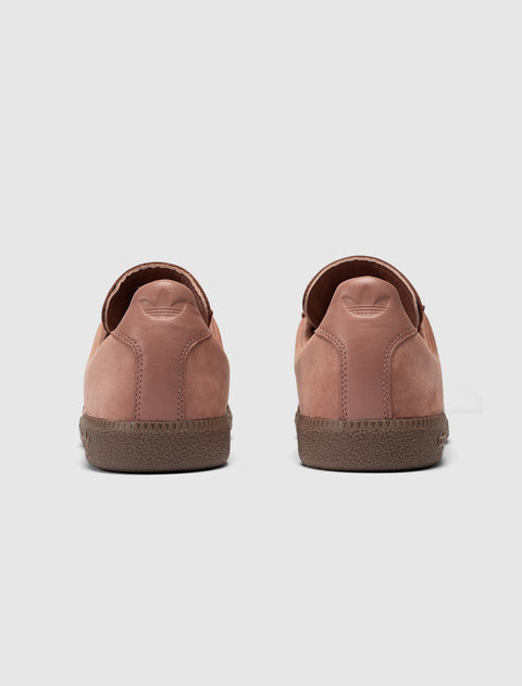 Back view of salmon pink suede low-top sneakers on light background