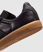 Close-up of a dark leather sneaker with gum sole and adidas logo, streetwear shoe detail
