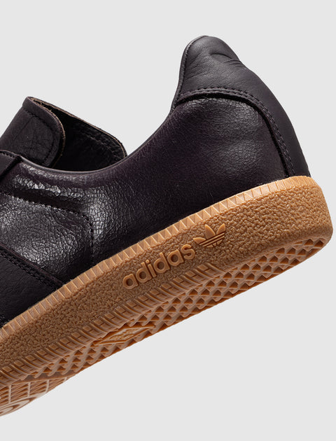 Close-up of a dark leather sneaker with gum sole and adidas logo, streetwear shoe detail