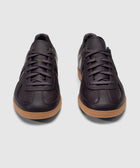 Pair of dark purple leather sneakers with gum sole on a white background