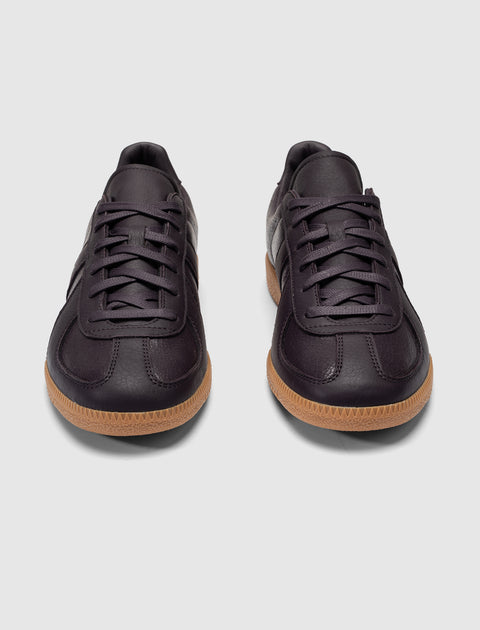 Pair of dark purple leather sneakers with gum sole on a white background