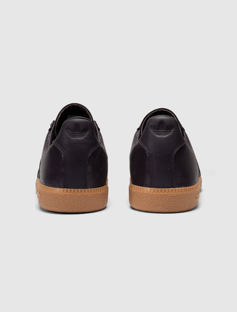 Back view of dark purple low-top sneakers with gum soles on a plain background
