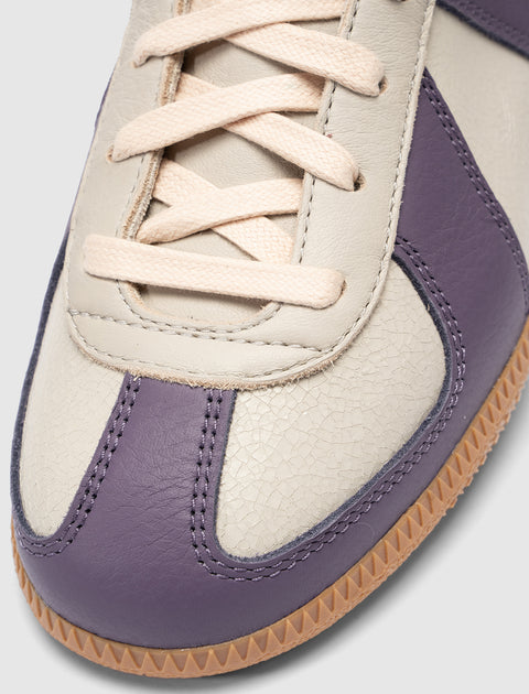 Close-up of a cream and purple leather sneaker with beige laces and gum sole