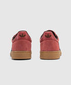 Back view red suede low-top sneakers with gum soles and black accents on white background