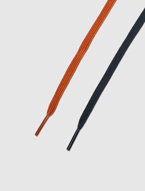 Close-up of orange and black flat shoelaces on a white background