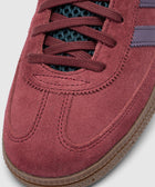 Close-up of red suede sneaker toe with dark laces and gum rubber sole