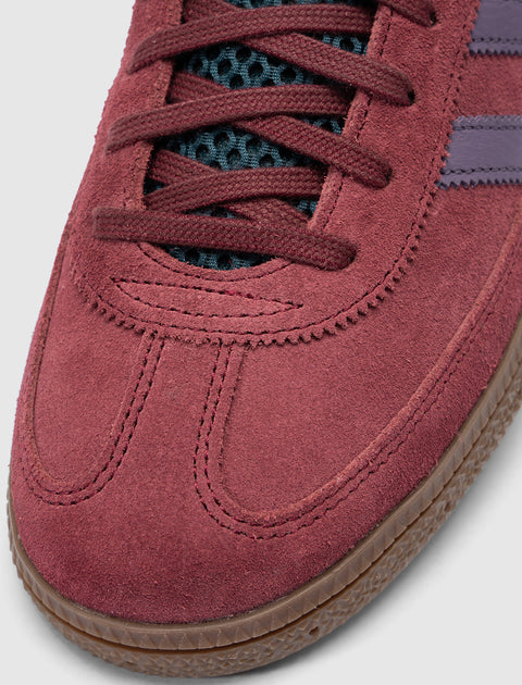 Close-up of red suede sneaker toe with dark laces and gum rubber sole