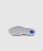White sneaker outsole with wavy traction pattern and blue accent on heel, studio background
