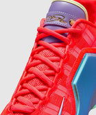 Close-up vibrant red sneaker with purple tongue, gold signature detail, and blue accents