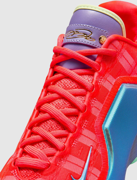 Close-up vibrant red sneaker with purple tongue, gold signature detail, and blue accents