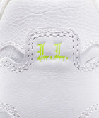 Close-up of white leather sneaker heel with neon green 'L.L.' embroidery detail