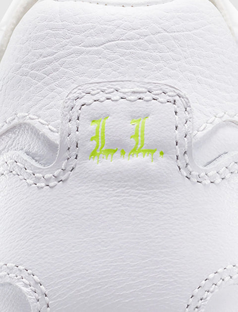 Close-up of white leather sneaker heel with neon green 'L.L.' embroidery detail