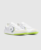 White low-top sneakers with grey star details and neon green soles on a plain background