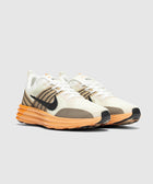 Men's white and brown sneakers with orange sole, black swoosh, modern streetwear style