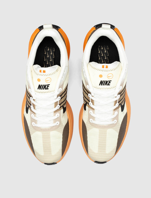 Top view of Nike sneakers in beige, brown, and orange with white laces on a gray background